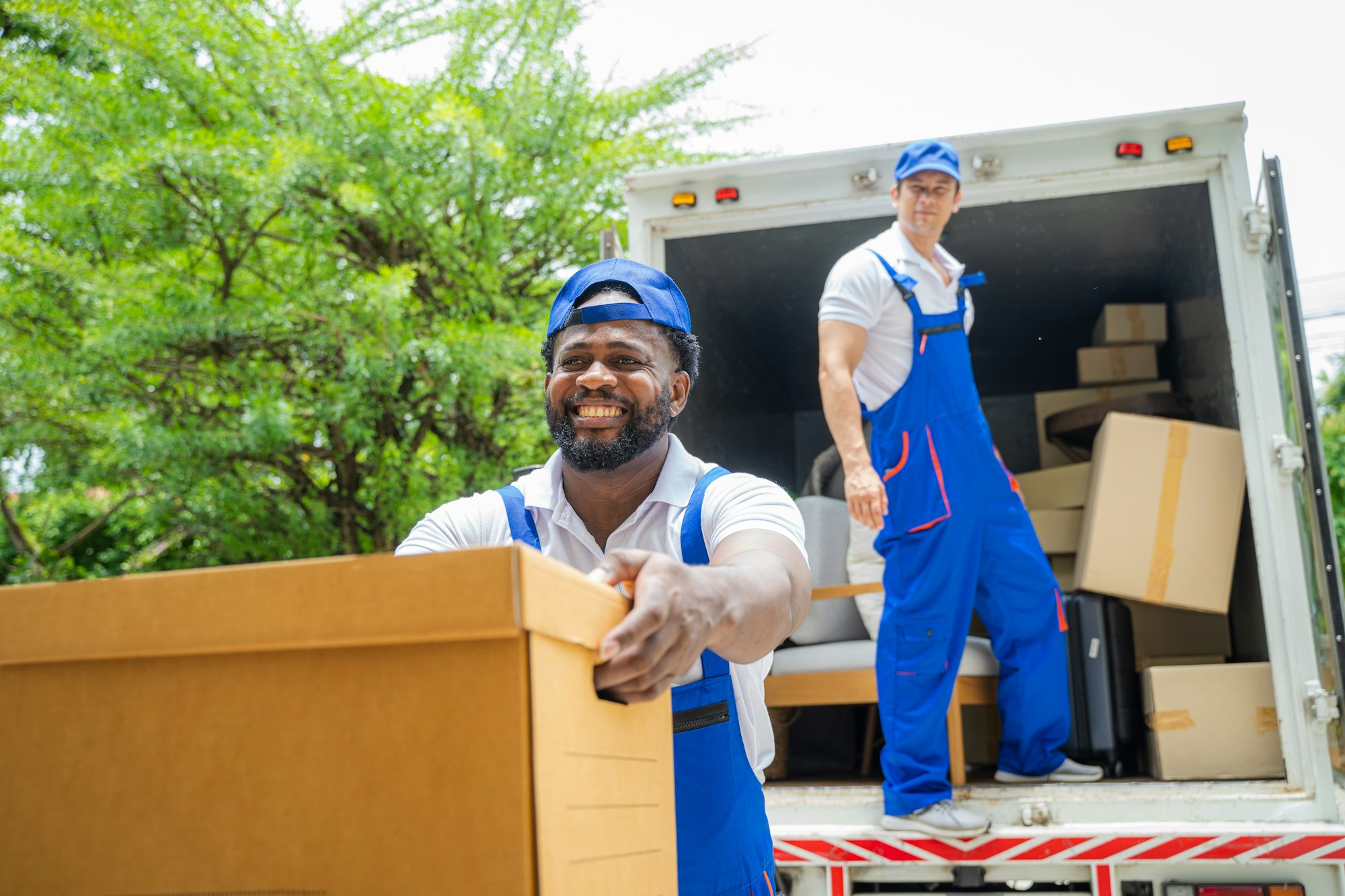 Delivery man unloading moving boxes from car into new home on moving day.